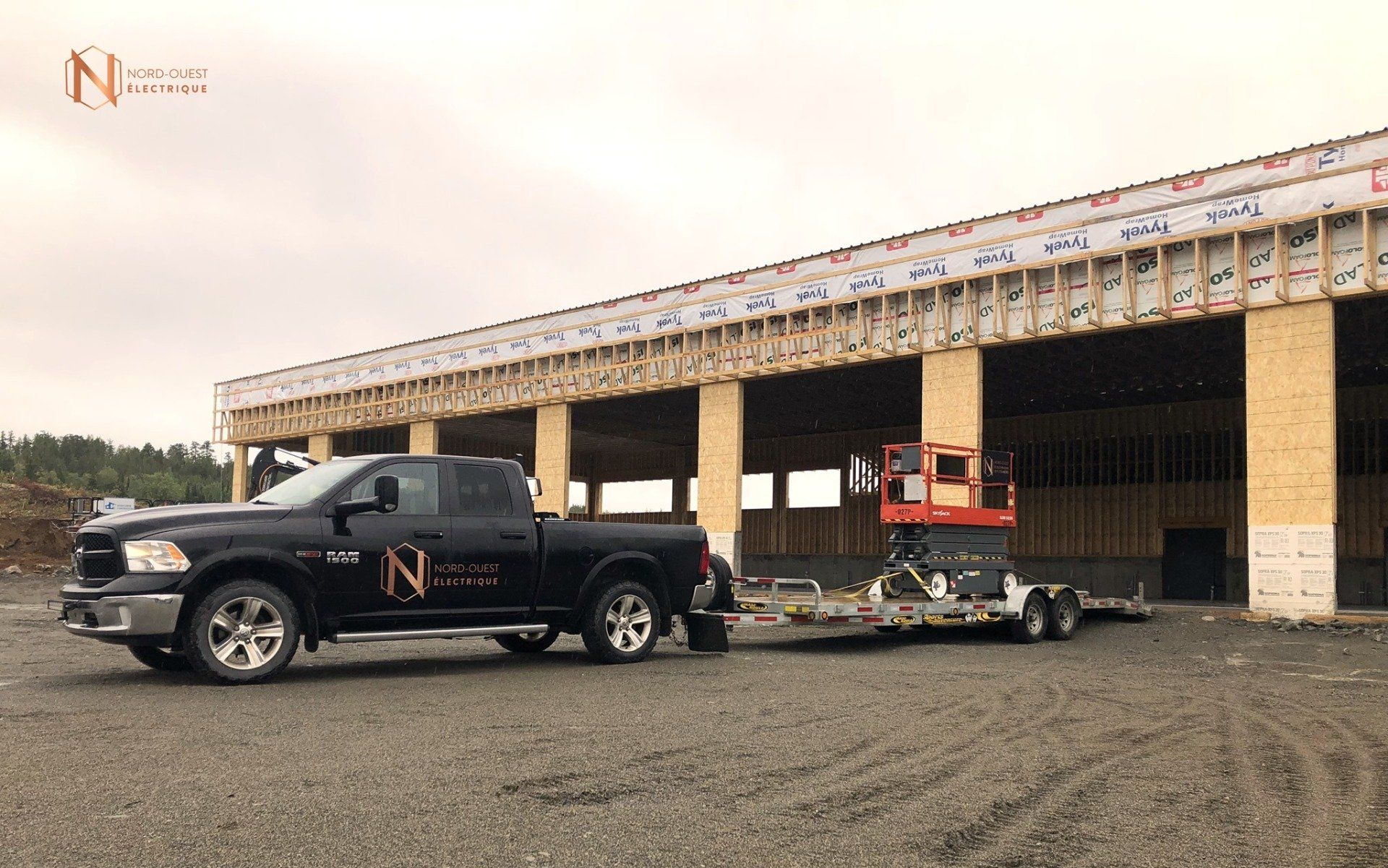 Un camion tracte une remorque devant un bâtiment en construction.