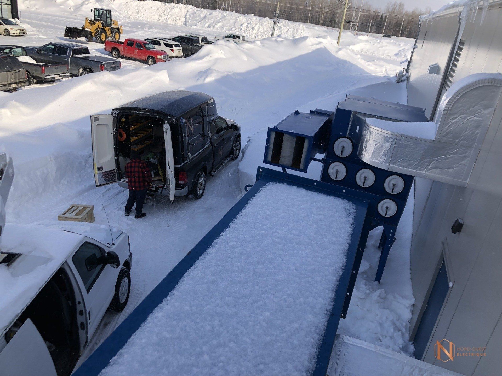 Un camion est garé dans la neige à côté d'une machine.