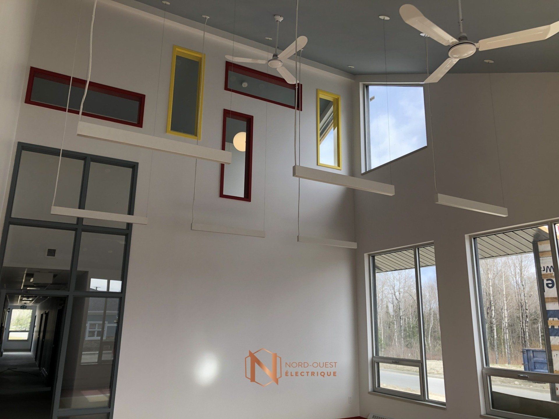 Une pièce avec beaucoup de fenêtres et des ventilateurs de plafond suspendus au plafond.