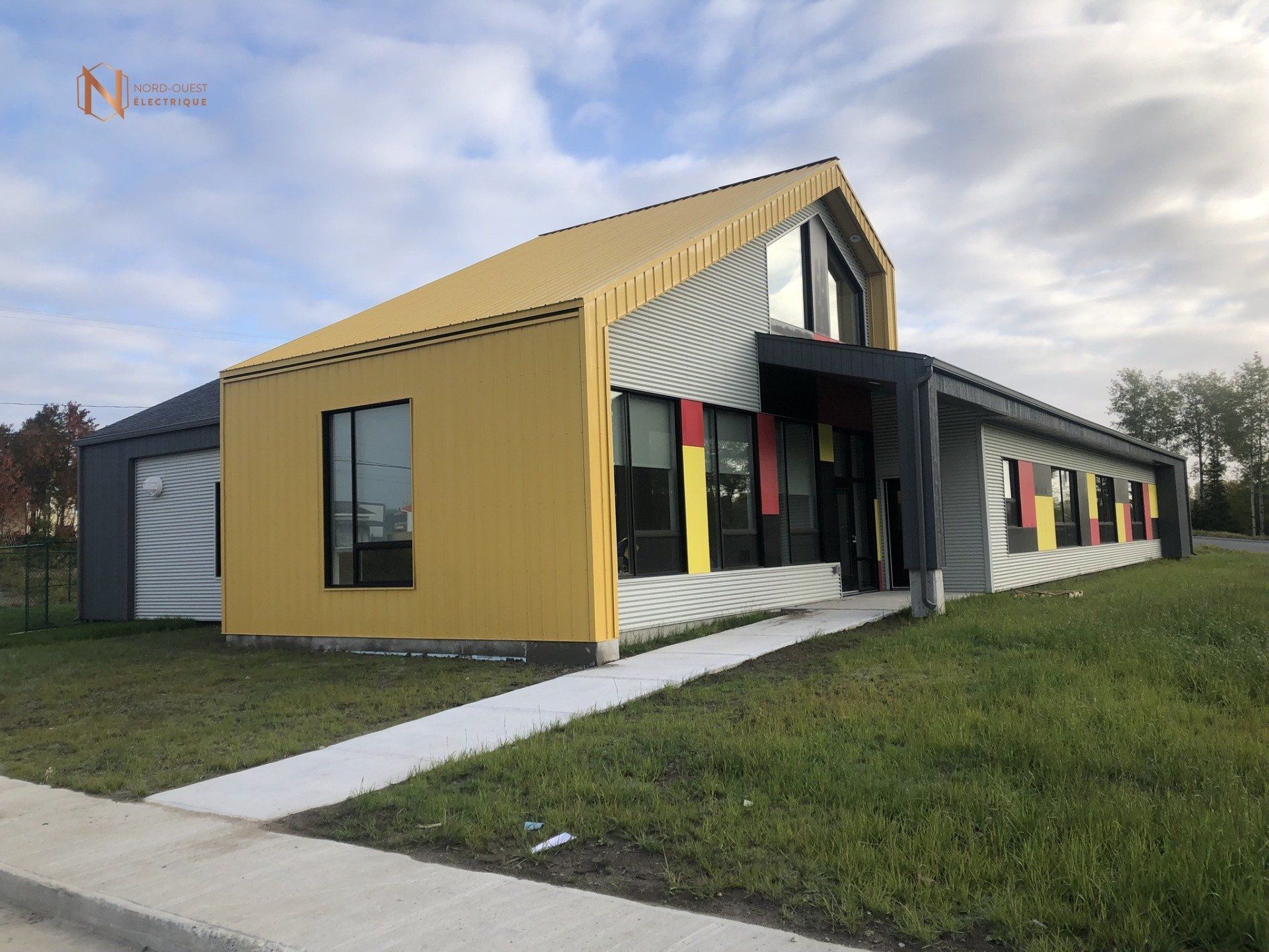 Un grand bâtiment avec un toit jaune se trouve au milieu d'un champ herbeux.