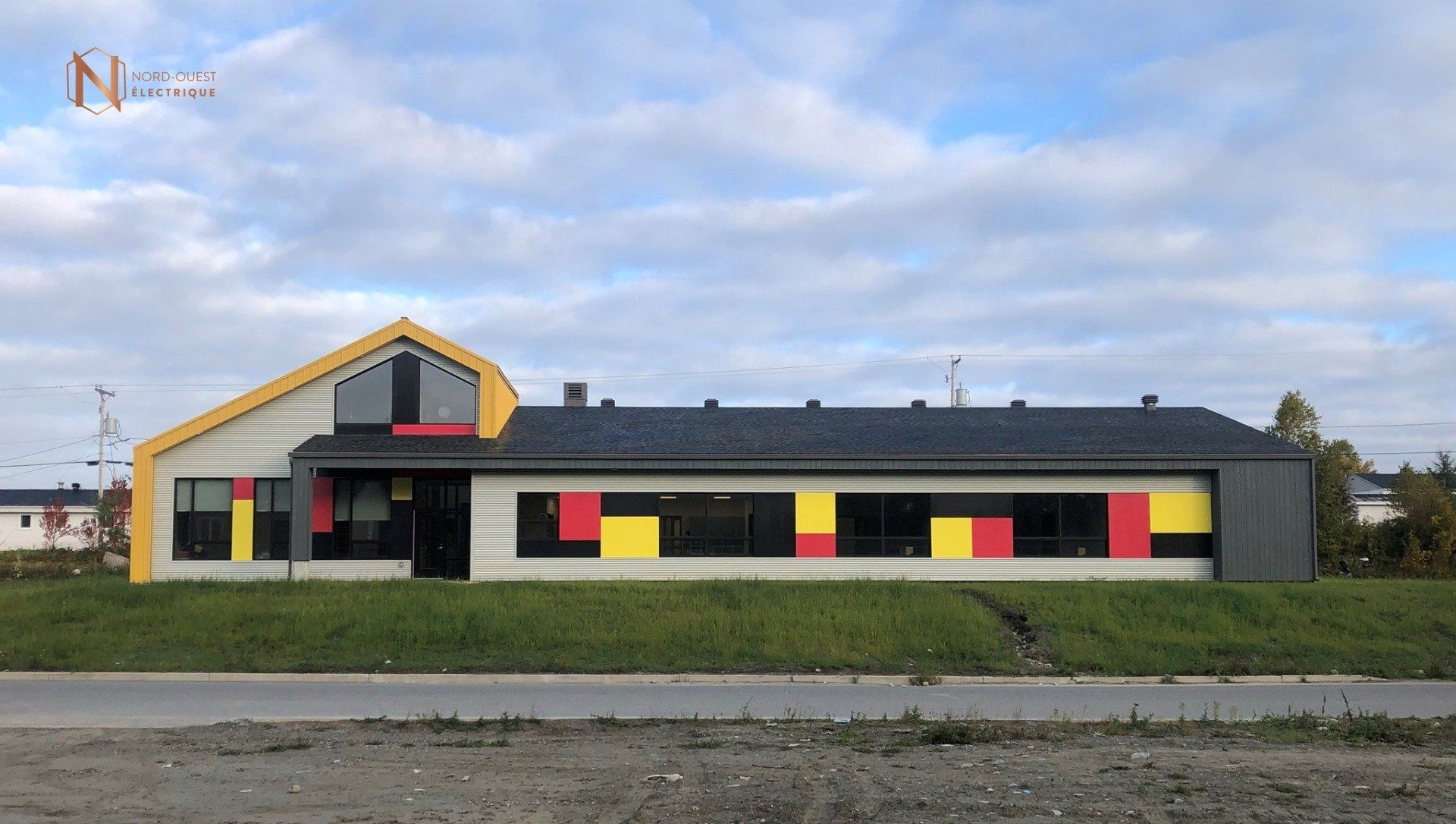 Un grand bâtiment avec beaucoup de fenêtres se trouve au milieu d'un champ.