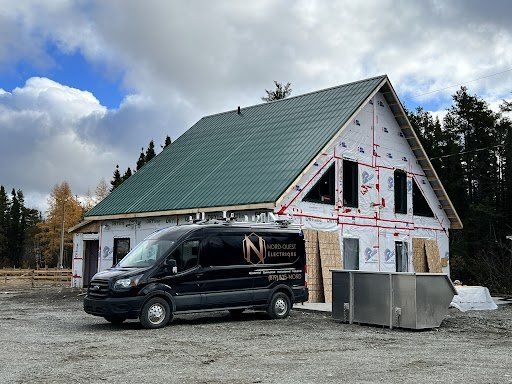Une camionnette noire est garée devant une maison en construction.