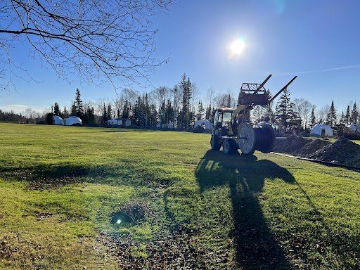 Un tracteur est garé dans un champ herbeux par une journée ensoleillée.