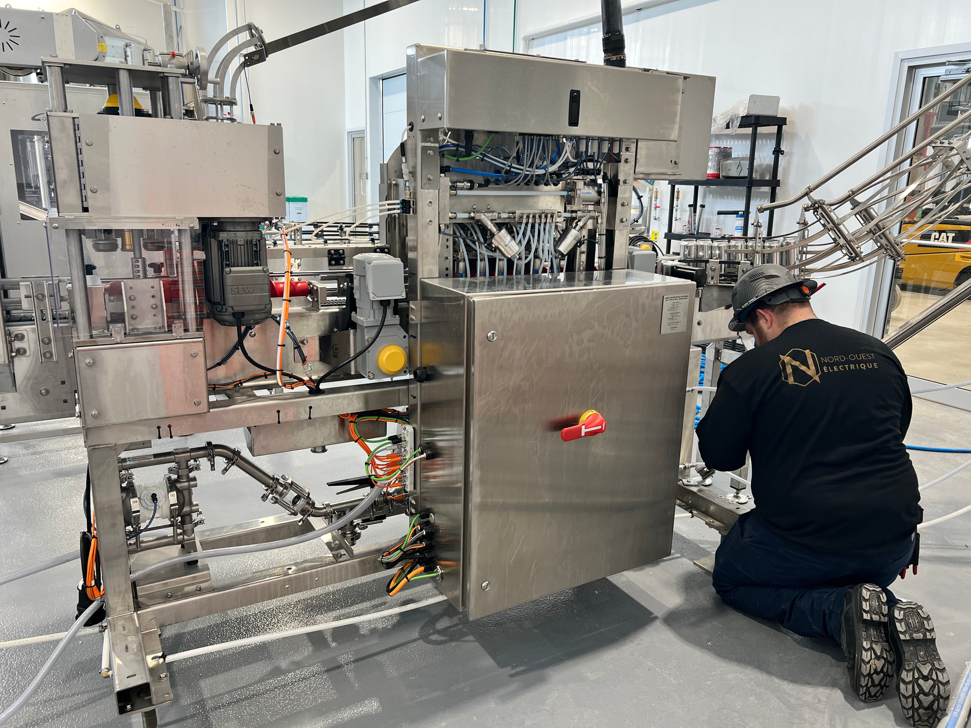 Un homme est agenouillé devant une machine dans une usine.