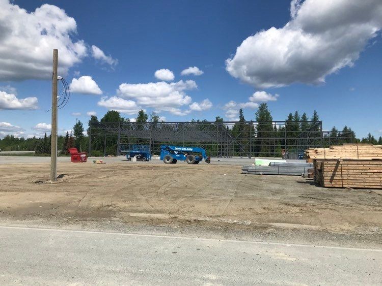 Un grand bâtiment est en construction dans un champ de terre.