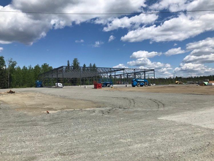 Un grand bâtiment est en construction au milieu d'un champ de terre.