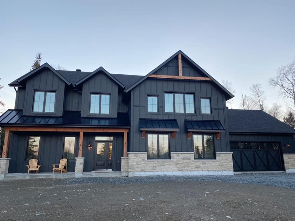 Une grande maison noire avec beaucoup de fenêtres et un garage