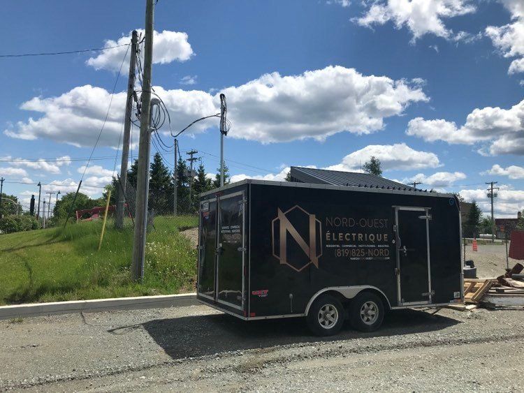 Une remorque noire est garée sur le bord de la route.