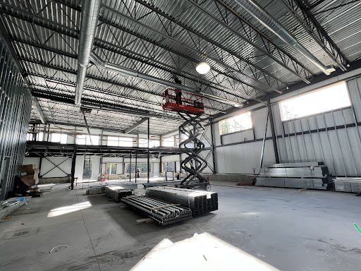 Un grand entrepôt avec un élévateur à ciseaux au milieu.