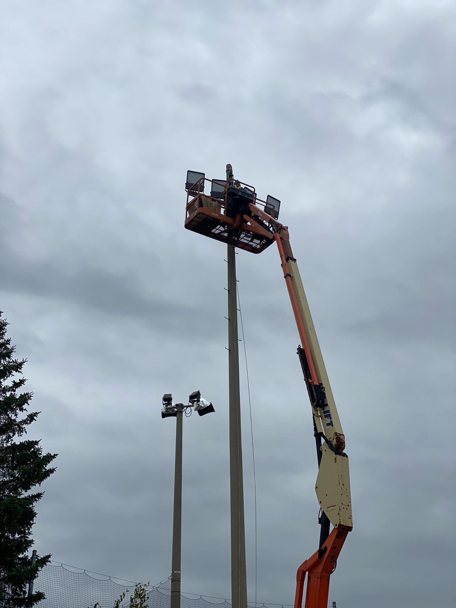 Une grue soulève un lampadaire dans le ciel.