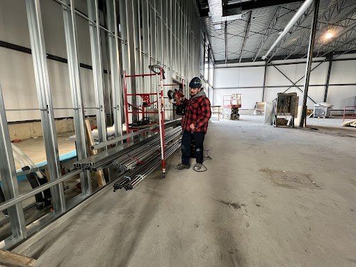 Un homme se tient debout dans un grand entrepôt et tient une perceuse.