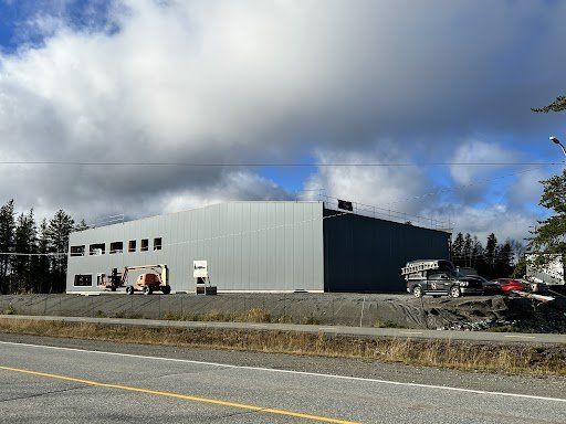 Un grand bâtiment gris se trouve à côté d'une route.