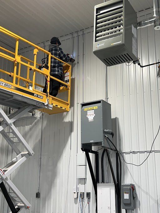 Un homme se tient debout sur une nacelle élévatrice à ciseaux et travaille sur un radiateur