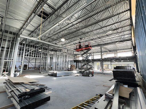 Un grand entrepôt en construction avec un élévateur à ciseaux.