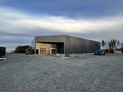 Un grand bâtiment est en construction sur un terrain en gravier.