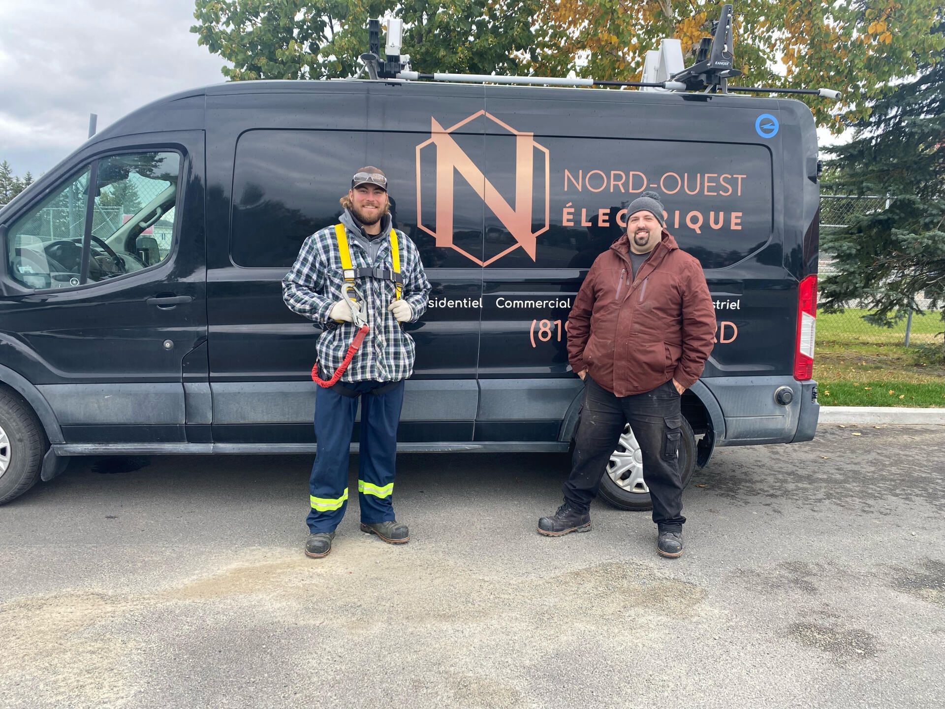 Deux hommes se tiennent devant une camionnette noire.