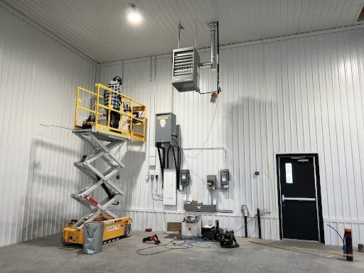 Un homme se tient debout sur un élévateur à ciseaux dans un bâtiment.