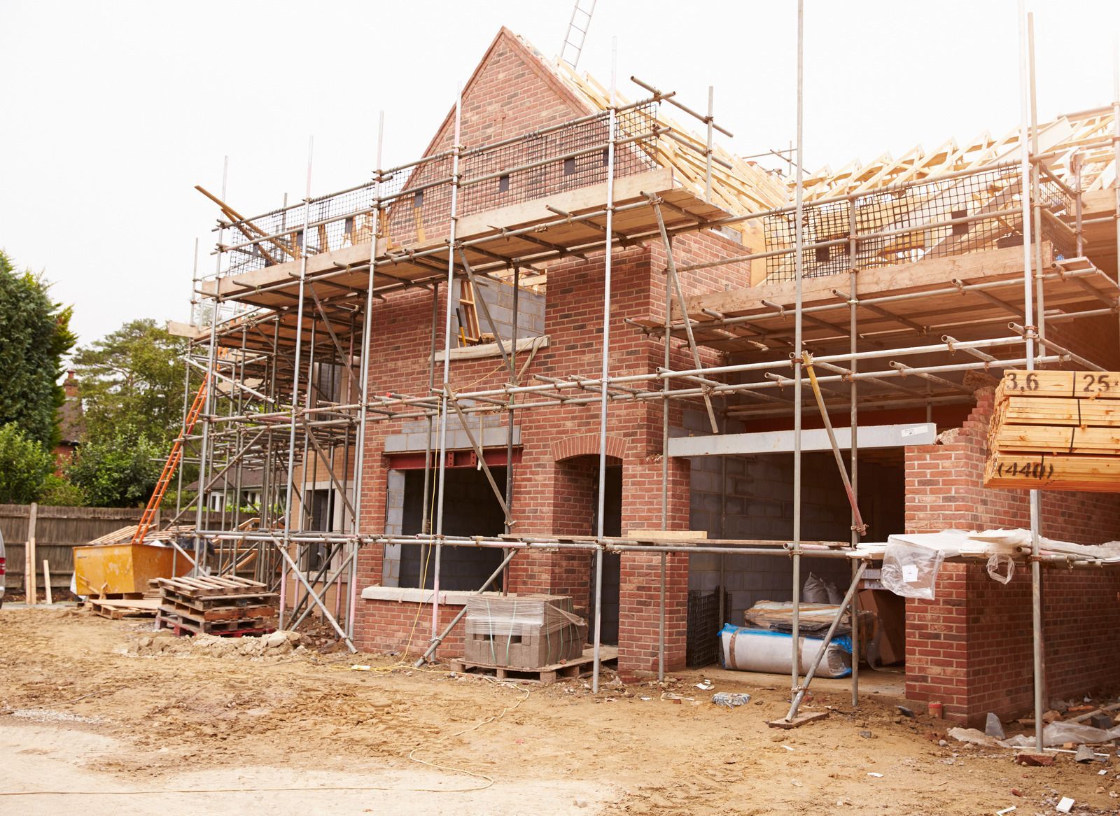 A large wooden house is being built with a blue sky in the background.