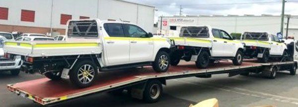 A Row of White Trucks Are Sitting on Top of A Flatbed Tow Truck — Welshpool, WA — PTE Group Pty Ltd
