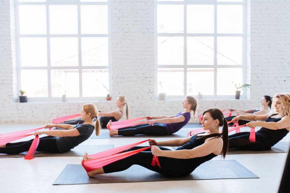 A Group Of Women Are Doing Exercises With A Resistance Band In A Gym — Caves Coastal Physiotherapy in Caves Beach, NSW