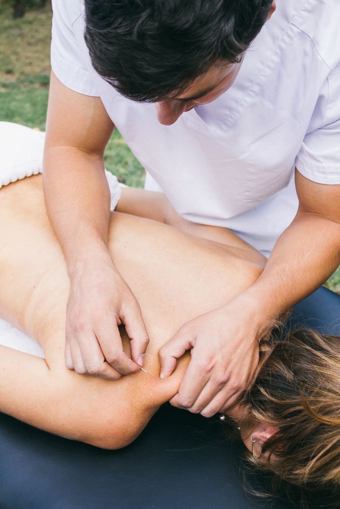 A Man Is Giving A Woman A Massage On A Table — Caves Coastal Physiotherapy in Caves Beach, NSW