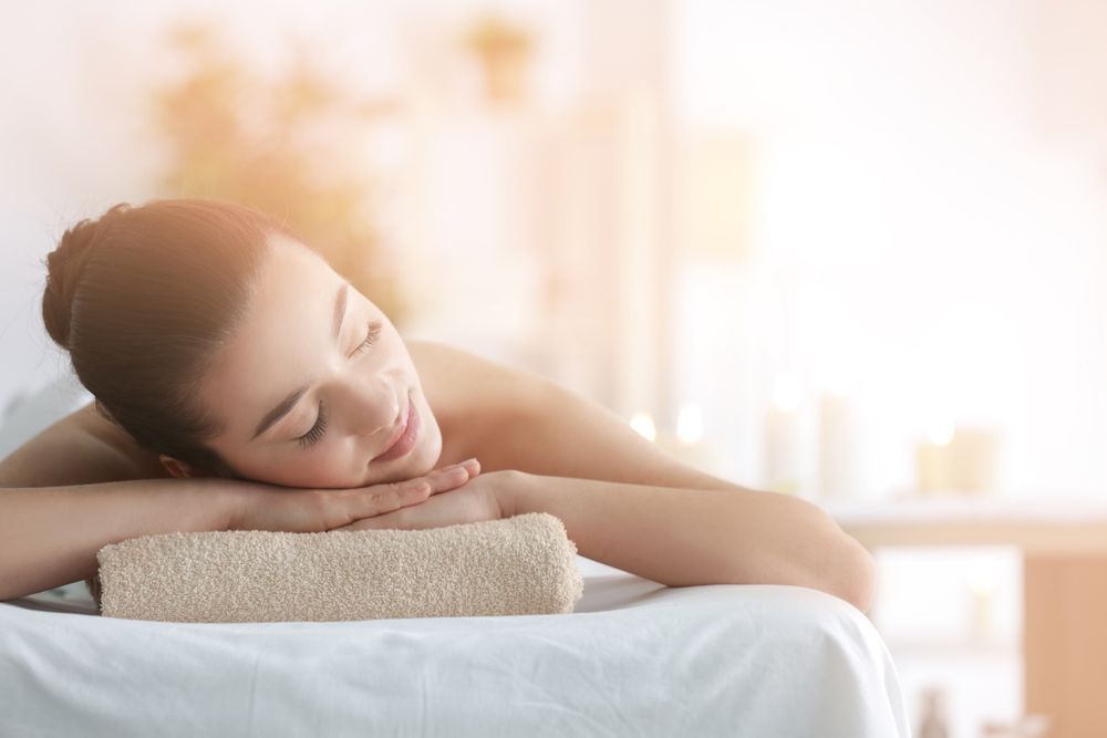 A Woman Is Laying On A Massage Table With Her Head On A Towel — Caves Coastal Physiotherapy in Swansea, NSW