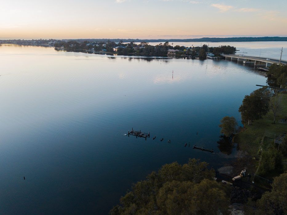 An Aerial View Of A Large Body Of Water With A Bridge In The Background — Caves Coastal Physiotherapy in Budgewoi, NSW