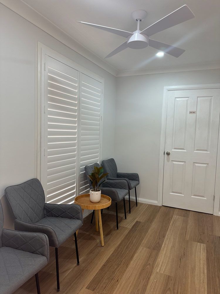 A Waiting Room With Chairs, A Table And A Ceiling Fan — Caves Coastal Physiotherapy in Caves Beach, NSW