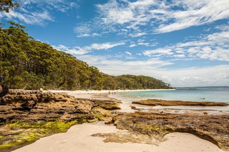 A Beach With A Lot Of Rocks And Trees In The Background — Caves Coastal Physiotherapy in Murrays Beach, NSW