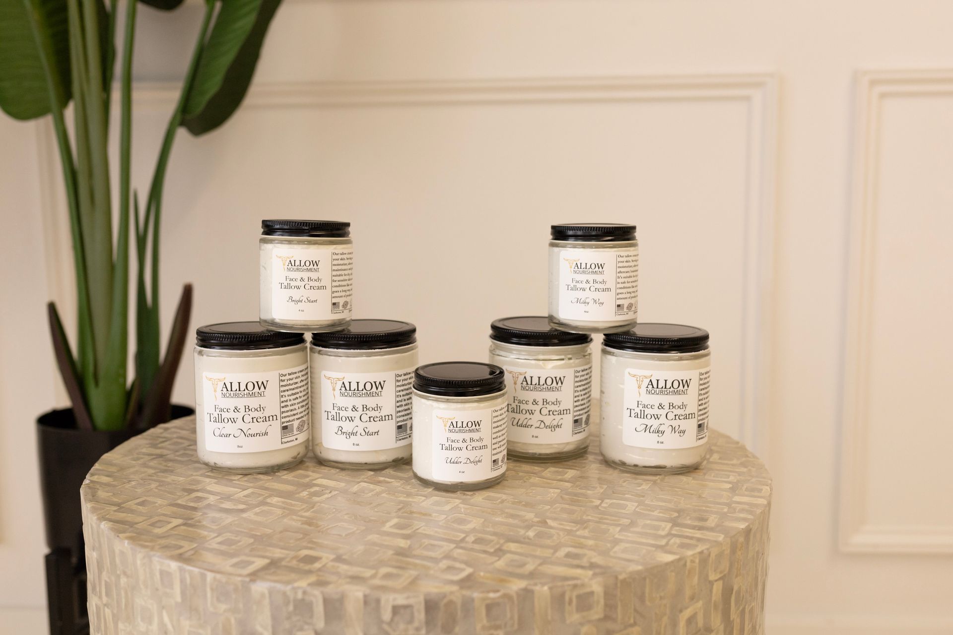 Allow Nourishment's Tallow Face & Body Creams are stacked on top of each other on a table.