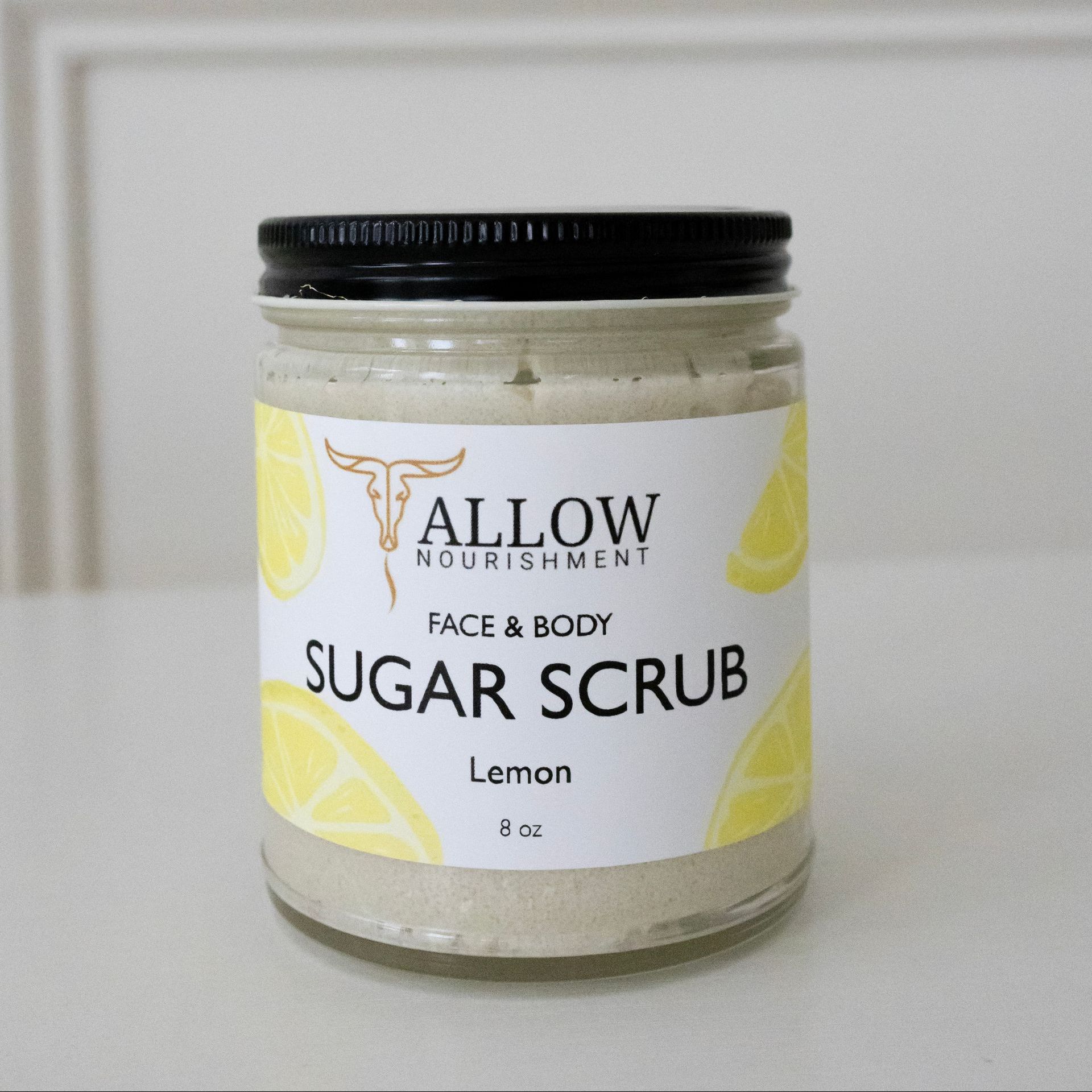 A jar of allow nourishment lemon tallow scrub on a table.