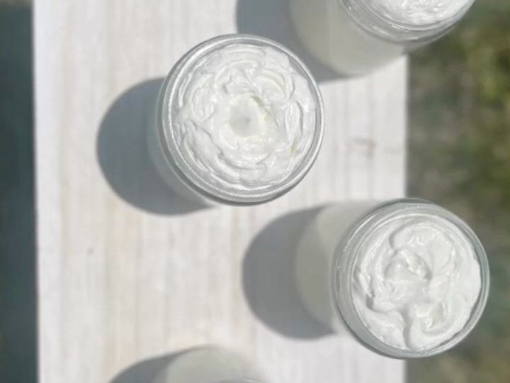 Three jars of tallow cream are sitting on top of a white table.