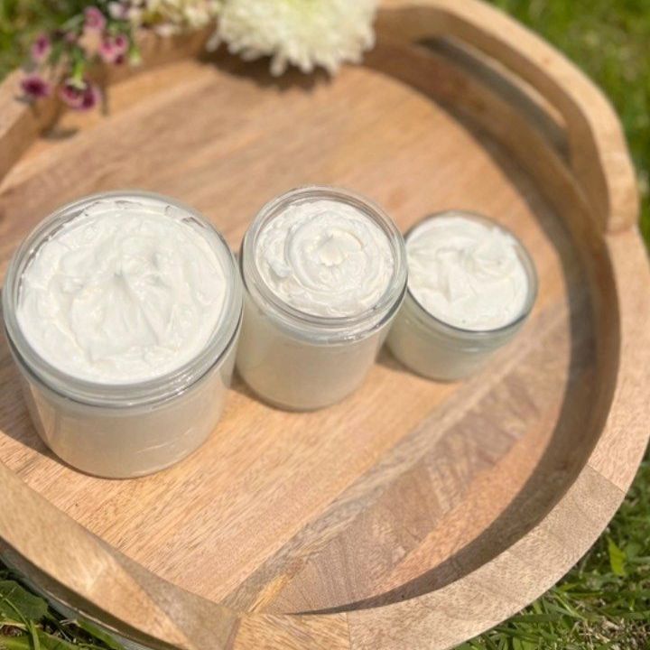 Three jars of tallow cream are sitting on a wooden tray.