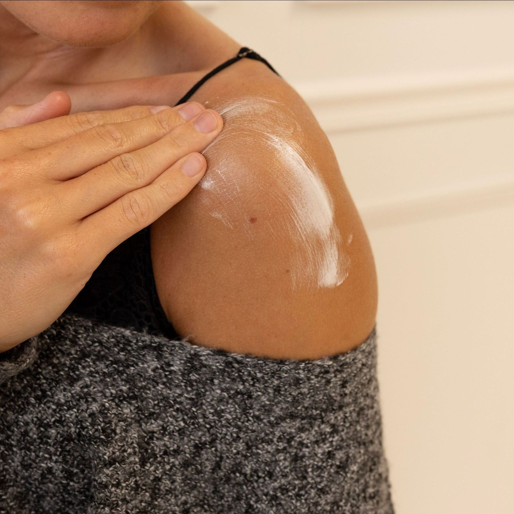 A woman is applying sunscreen to her shoulder / Allow Nourishment