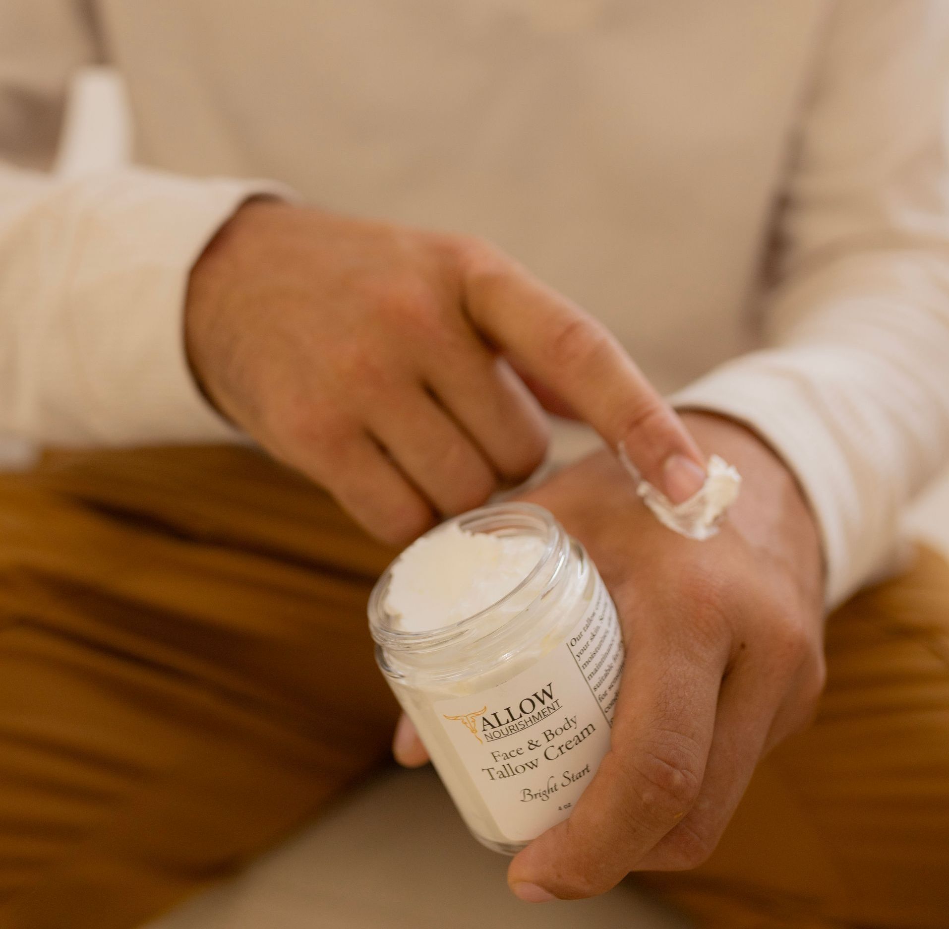 A person is applying Allow Nourishment skincare cream to their wrist