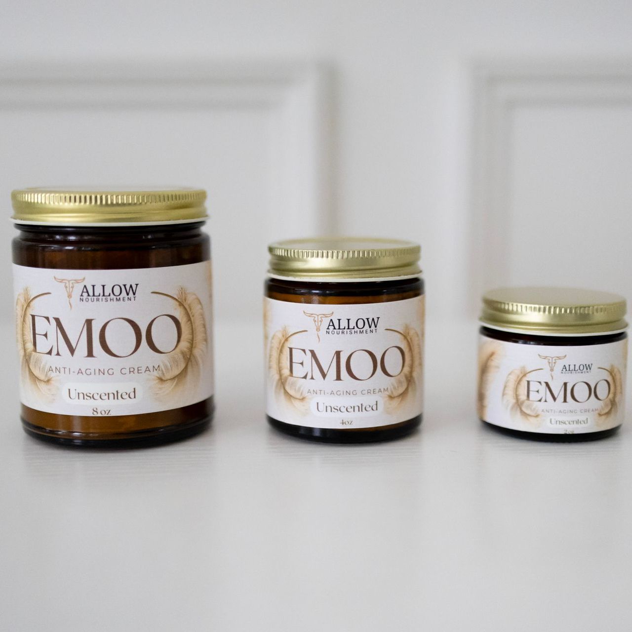 Three jars of Allow Nourishment's emoo anti-aging creams are sitting on a table.