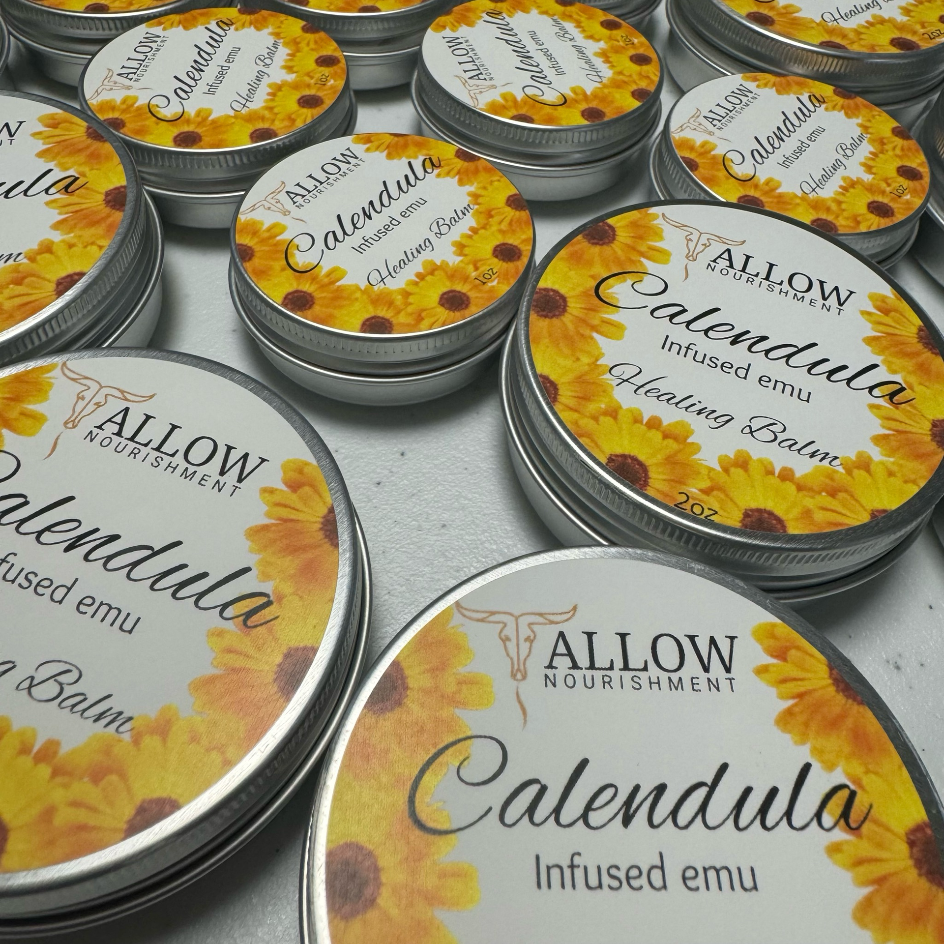 Several tins of calendula infused emu balm are stacked on top of each other