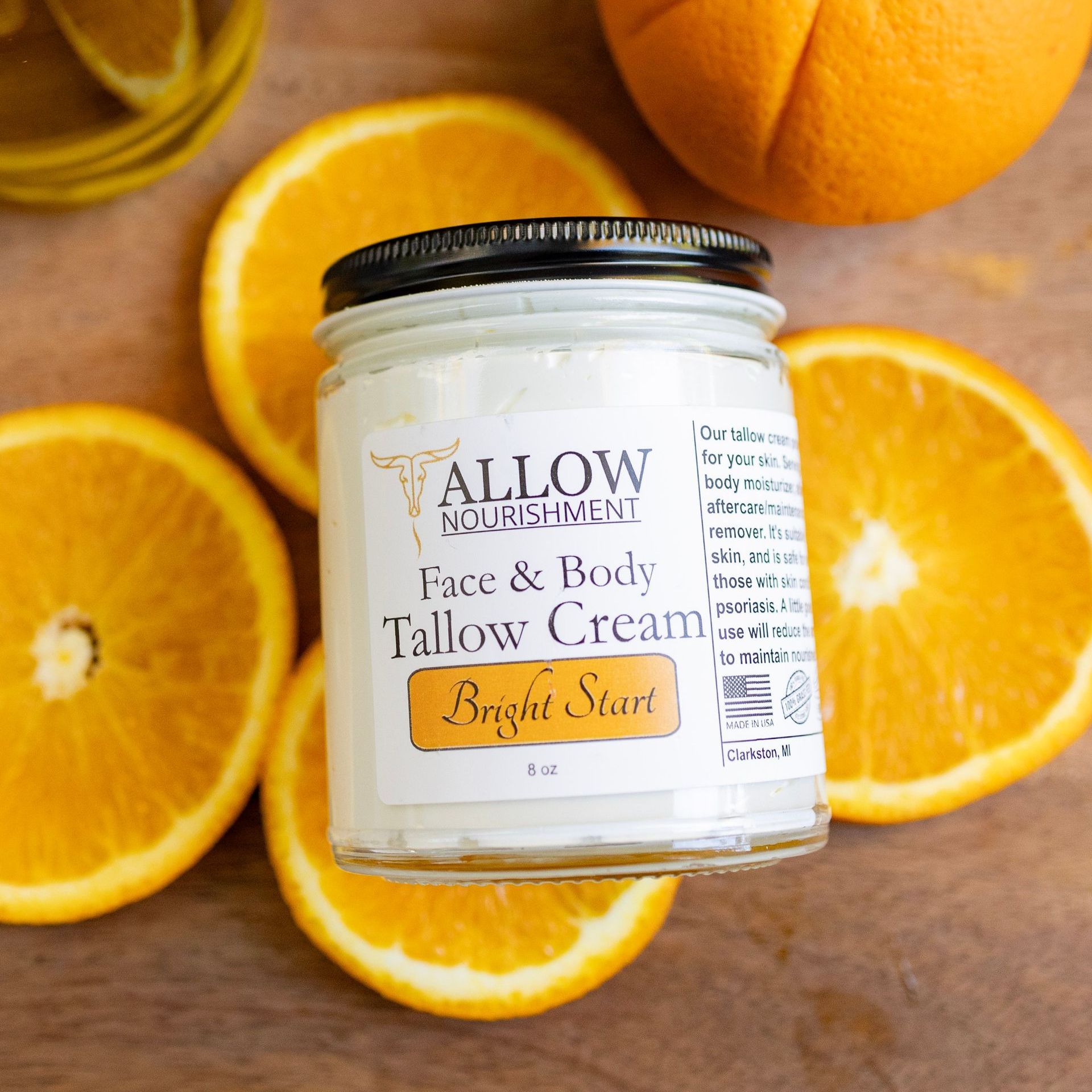 A jar of bright start  allow nourishment face and body tallow cream is surrounded by oranges