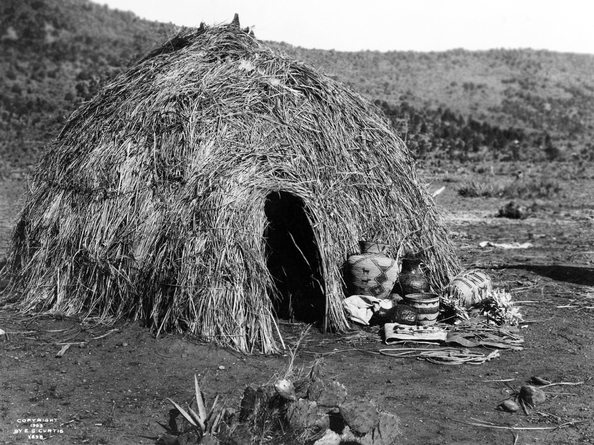 a black and white photo of a hut made of hay - Native Americans