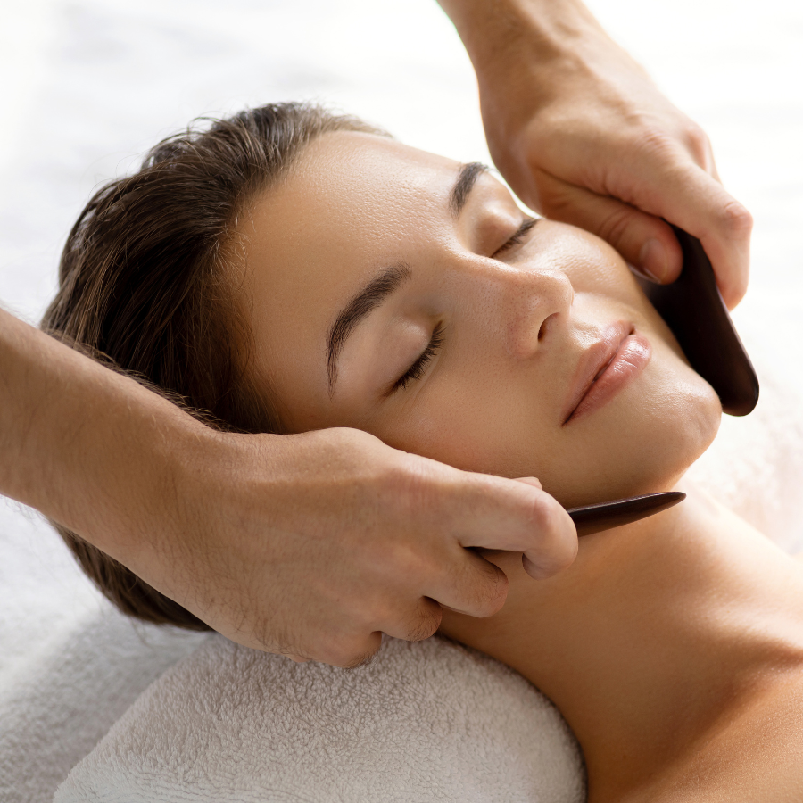 Allow Nourishment / Bian Gua Sha Stone is being used on a woman to massage her face.