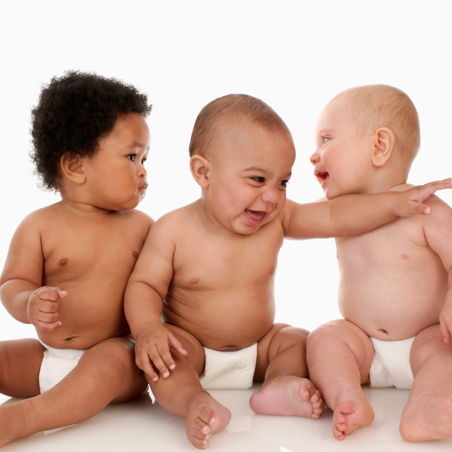 Allow Nourishment / Three babies are sitting next to each other and laughing and have diaper on. 