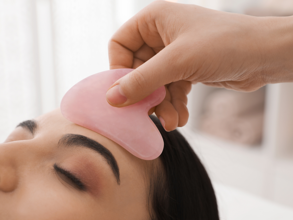 a woman is getting a pink gua sha massage on her forehead .