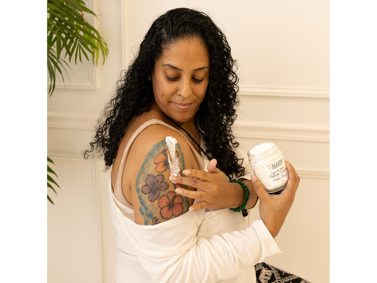 A woman putting Allow Nourishment face and body tallow cream on her tattoo to help with the healing process