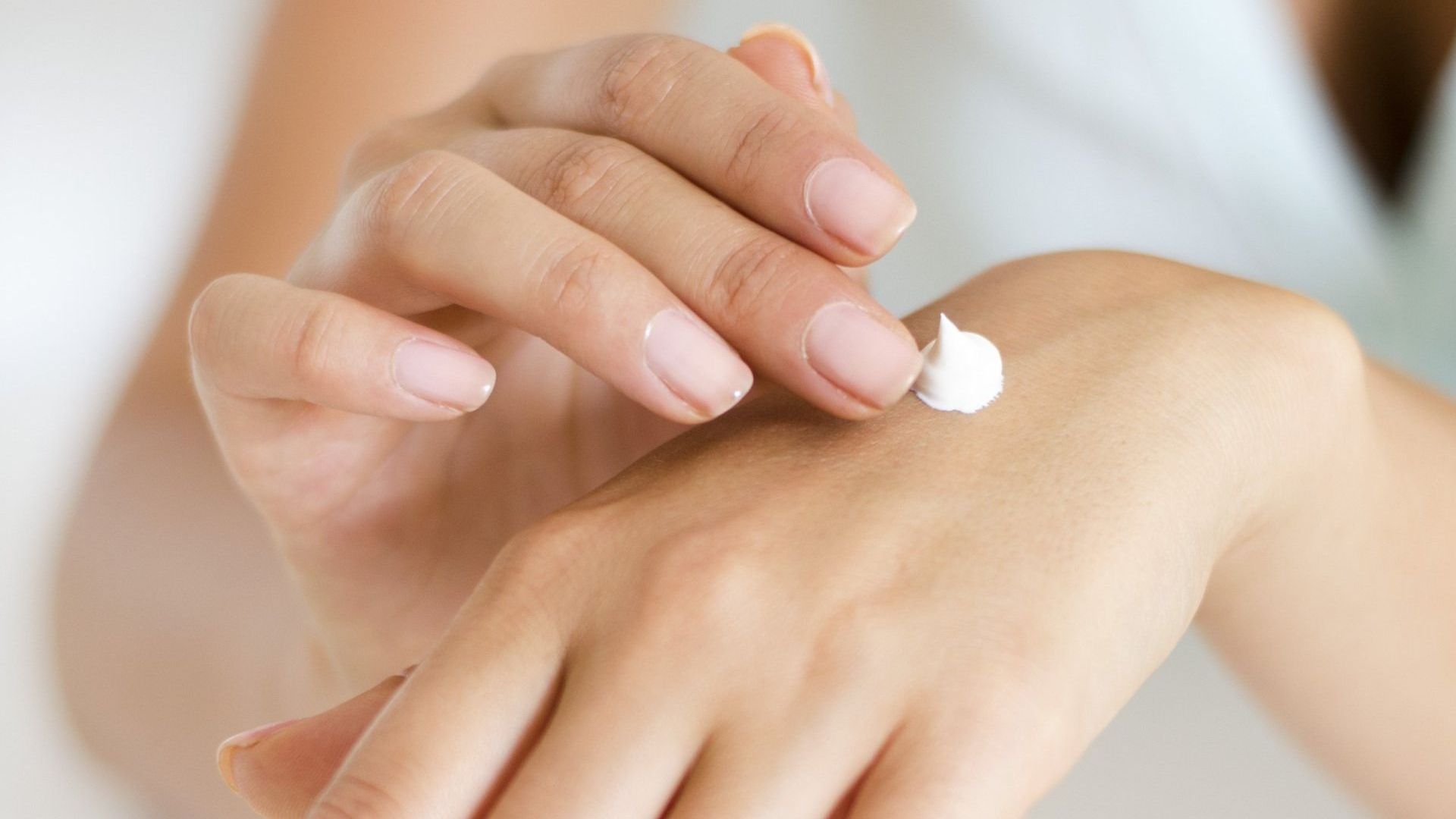 a woman is applying cream to her hand