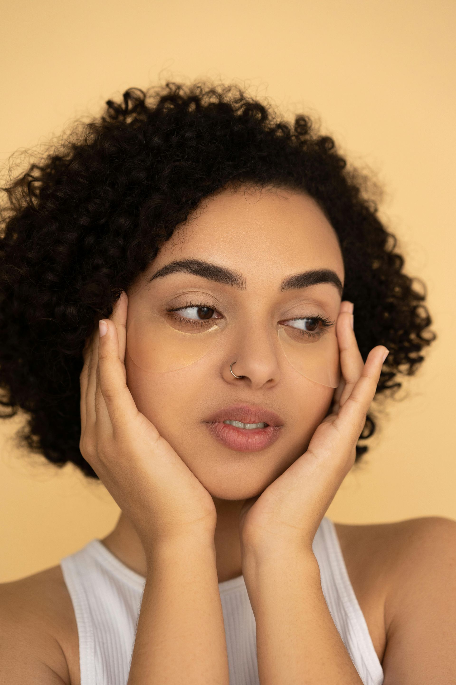 A woman with curly hair is holding her face with her hands.