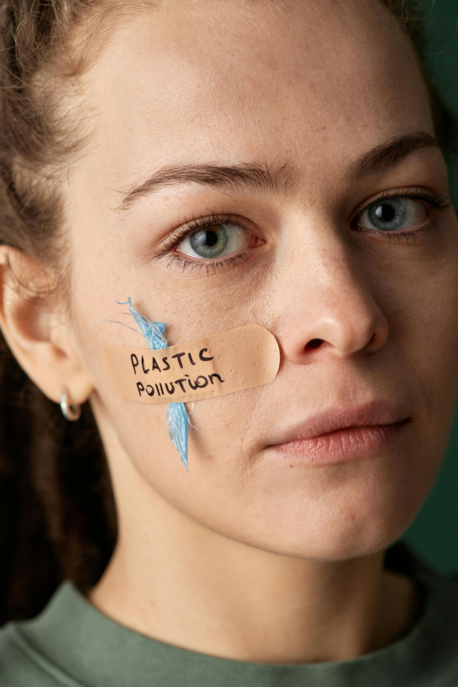 A woman has a bandage on her face that says plastic polution.