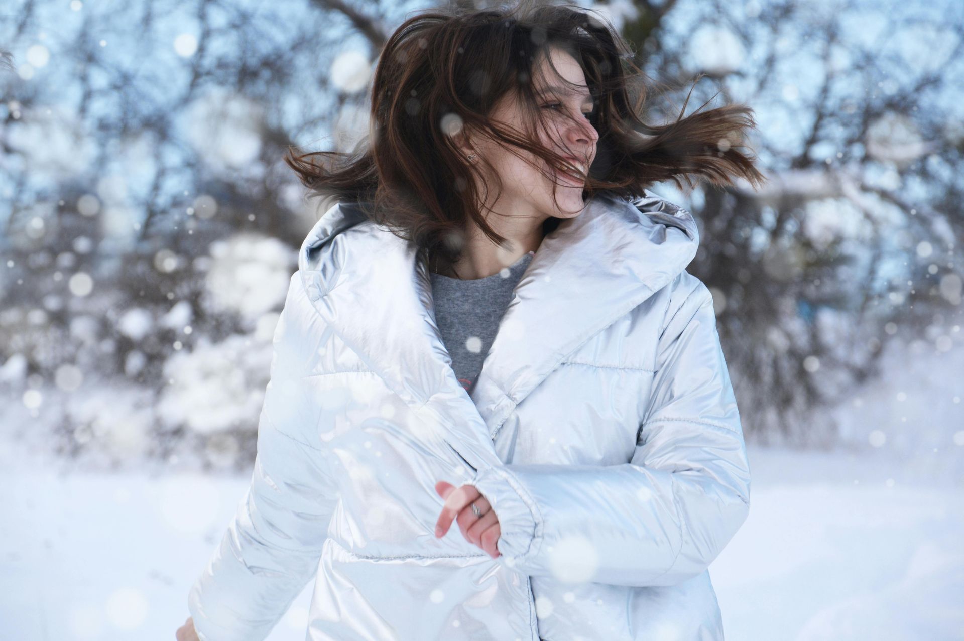 A woman in a white jacket is standing in the snow.