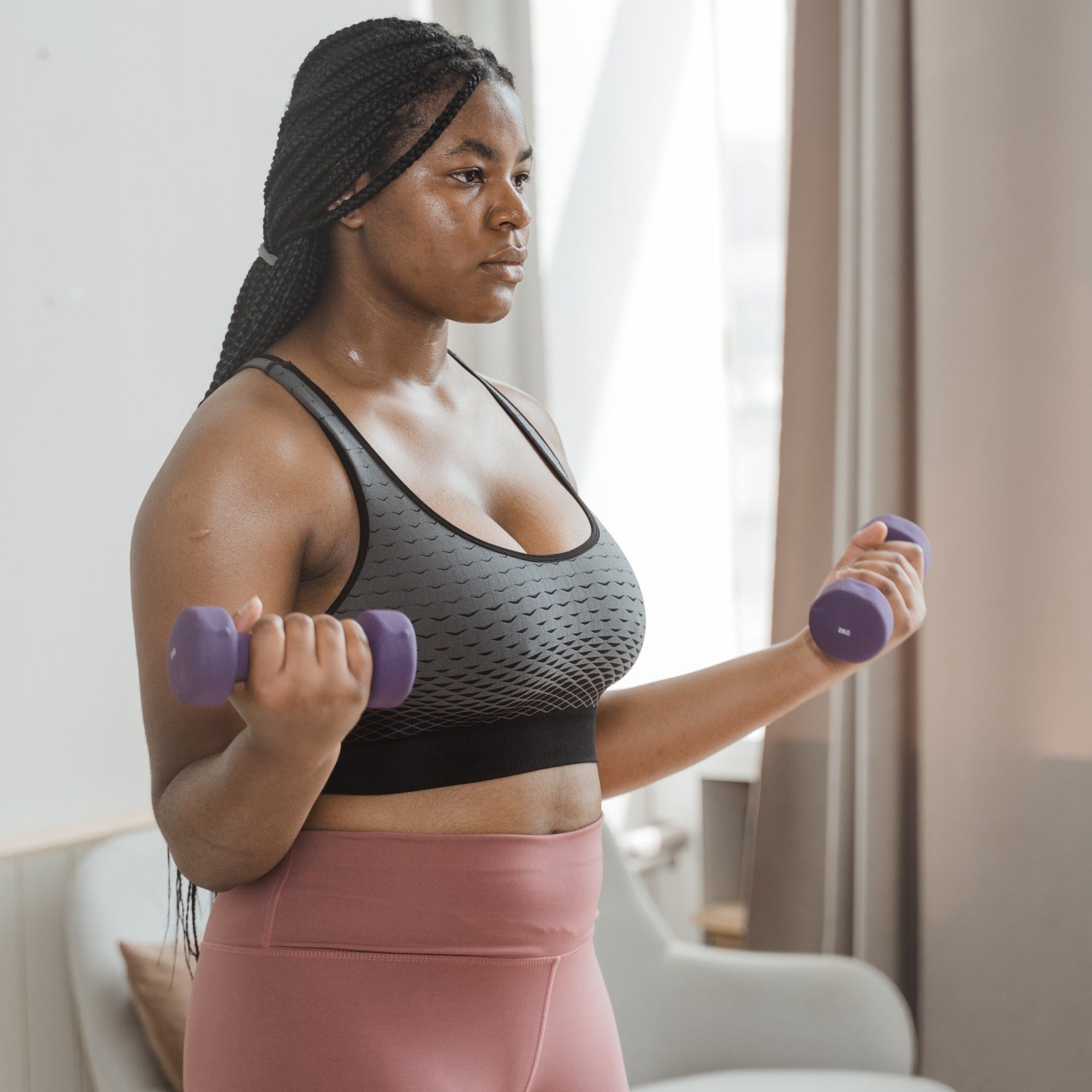 a woman is holding two purple dumbbells in her hands and sweating.