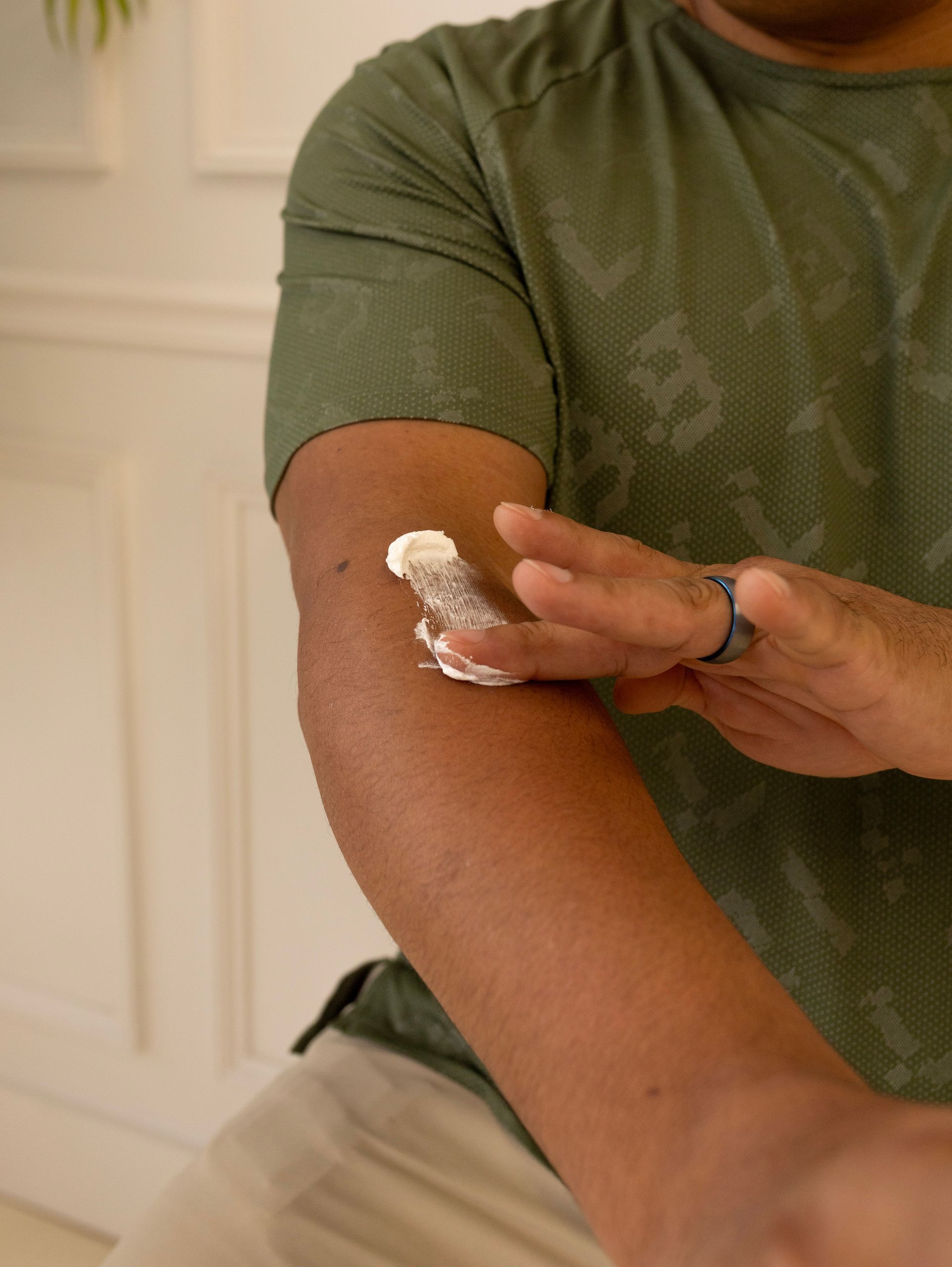 A man of color applying Clear Nourish Tallow & Body cream to his arm. Product by Allow Nourishment