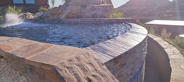 A white water tanker truck parked on a dirt lot with a hose extended towards the ground.